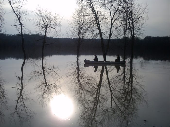 Brave people canoeing on a cold flooded lake